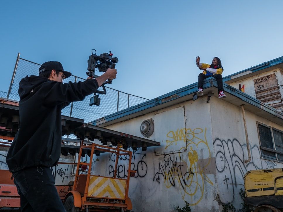 Man with black clothes and glasses holding a sony video camera