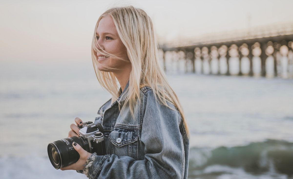 photographer standing on a seaside by a bridge