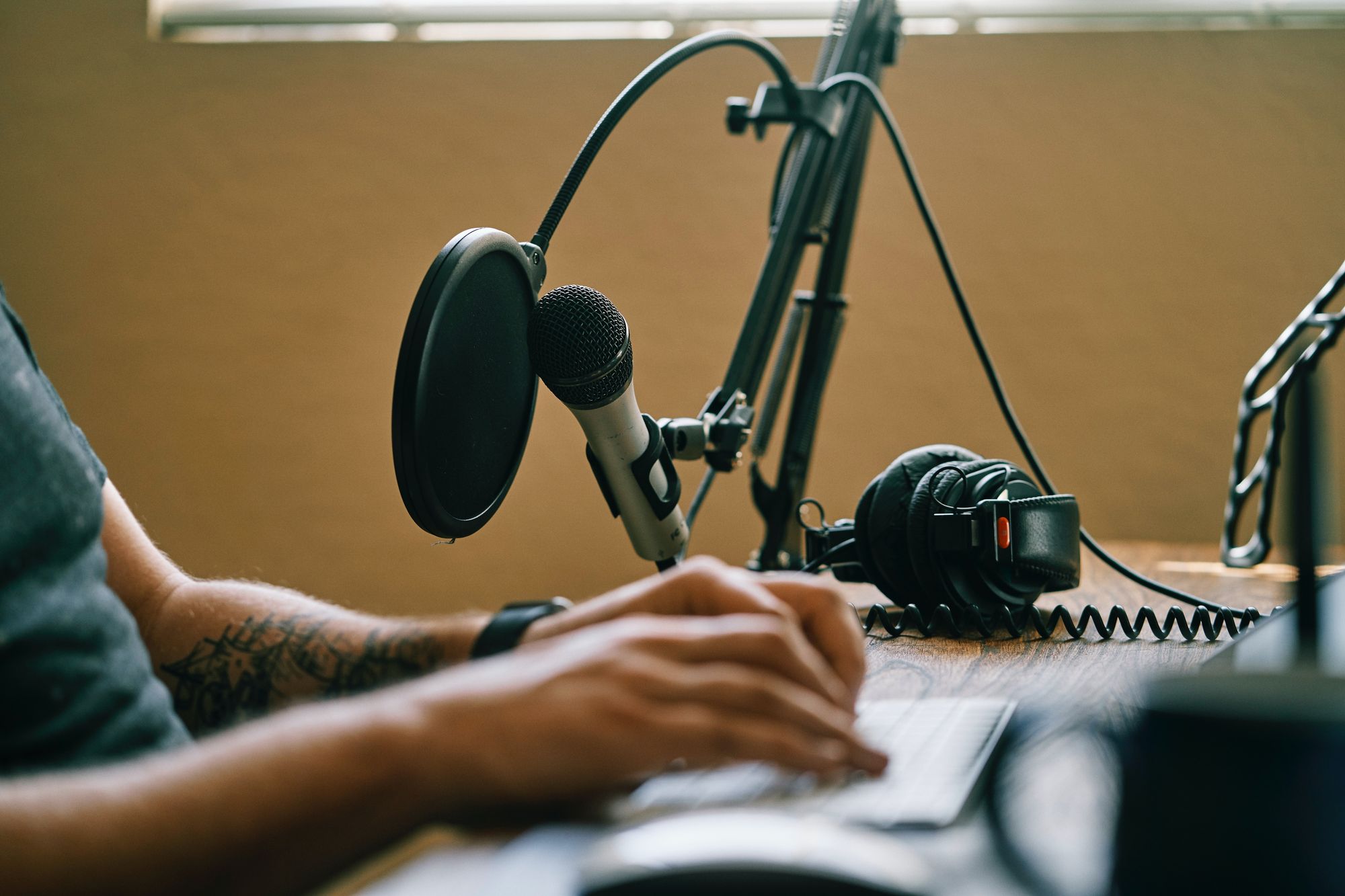 A man typing on the keyboard with podcast recording software on his left