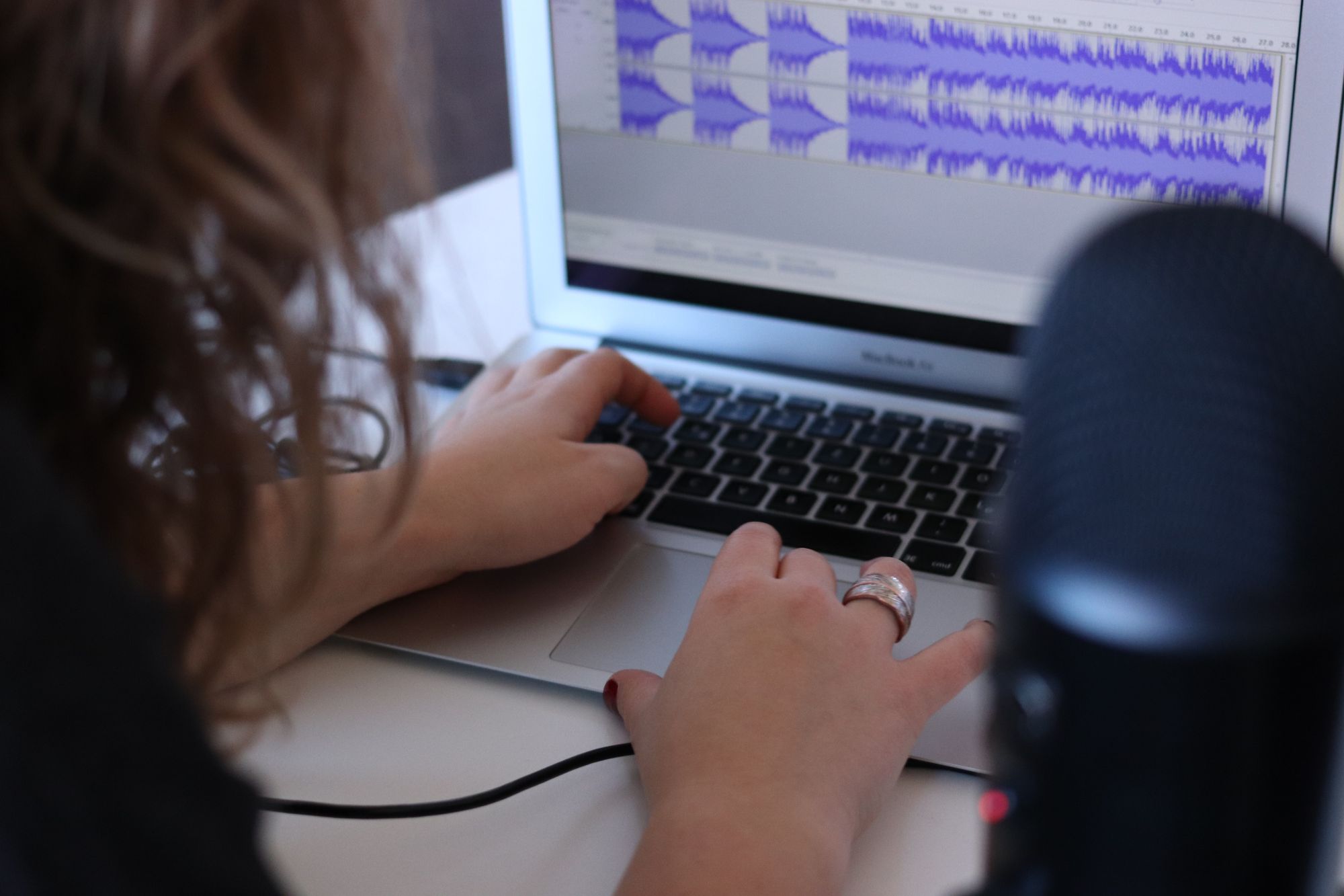 A woman editing audio files in a podcast editing software